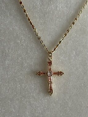 Rhinestone cross pendant on unmarked cable chain.